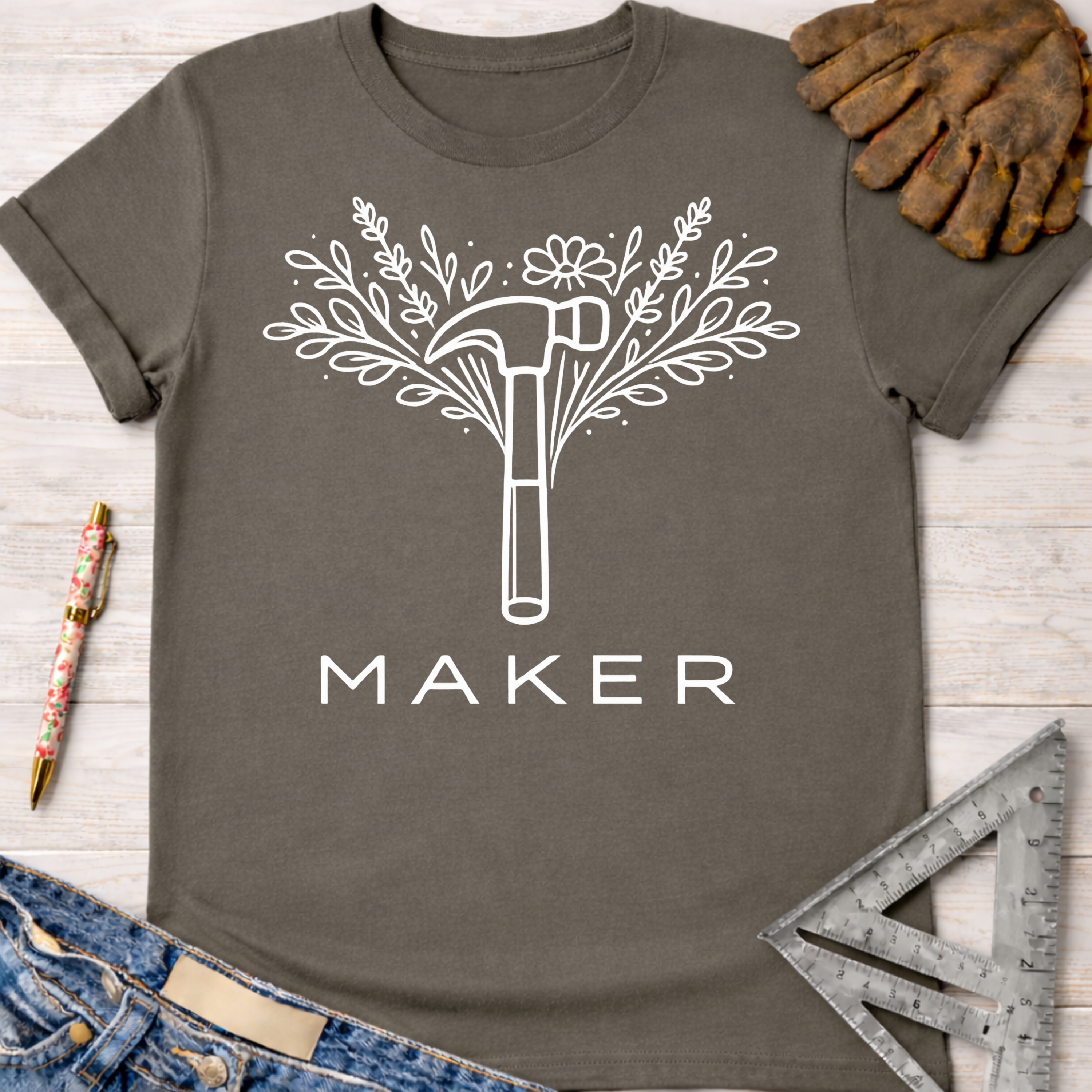 Women's funny woodworking graphic tee shirt for female woodworkers, makers, and DIY builders — Sawdust & Ponytails. Dark gray t-shirt with white floral hammer "MAKER" graphic.