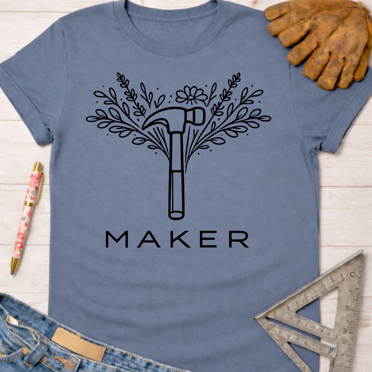 Women's funny woodworking graphic tee shirt for female woodworkers, makers, and DIY builders — Sawdust & Ponytails. Blue cotton tee with black floral hammer "MAKER" graphic.