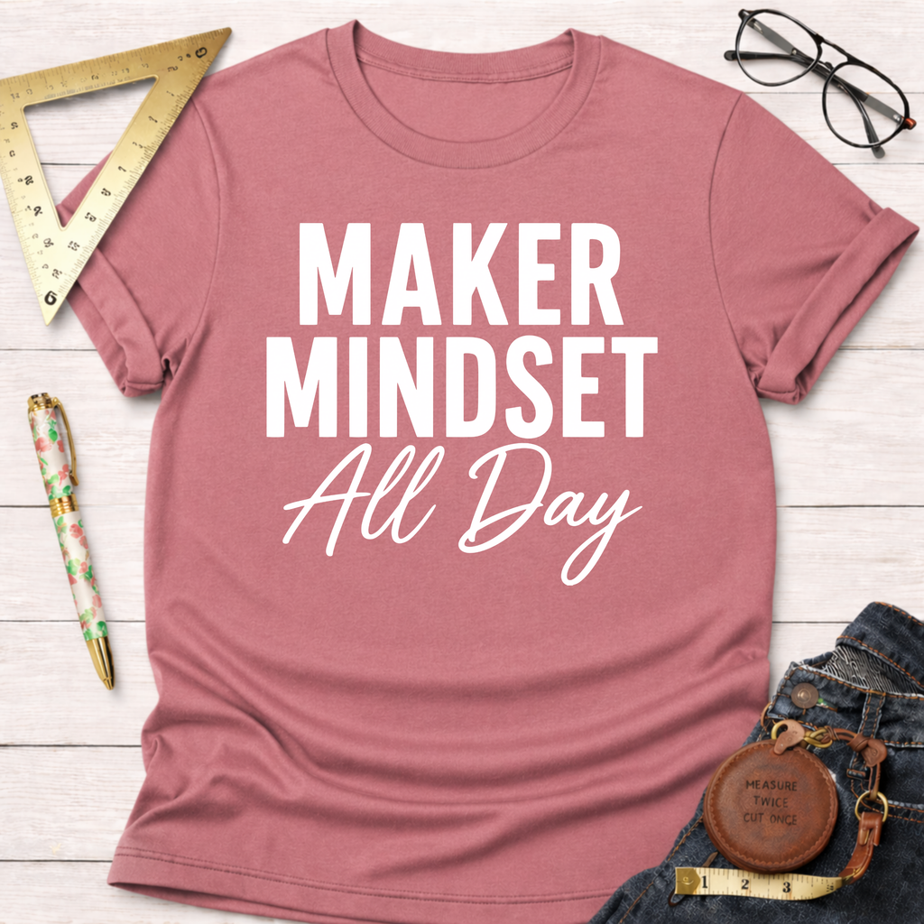 Pink cotton t-shirt with "MAKER MINDSET All Day" in white text, styled with jeans and tools.
