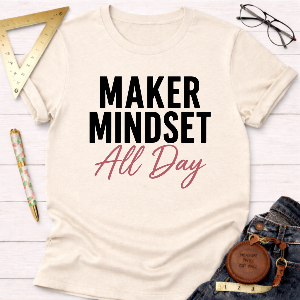 Cream "Maker Mindset All Day" graphic t-shirt with black and pink text, styled with jeans and tools.
