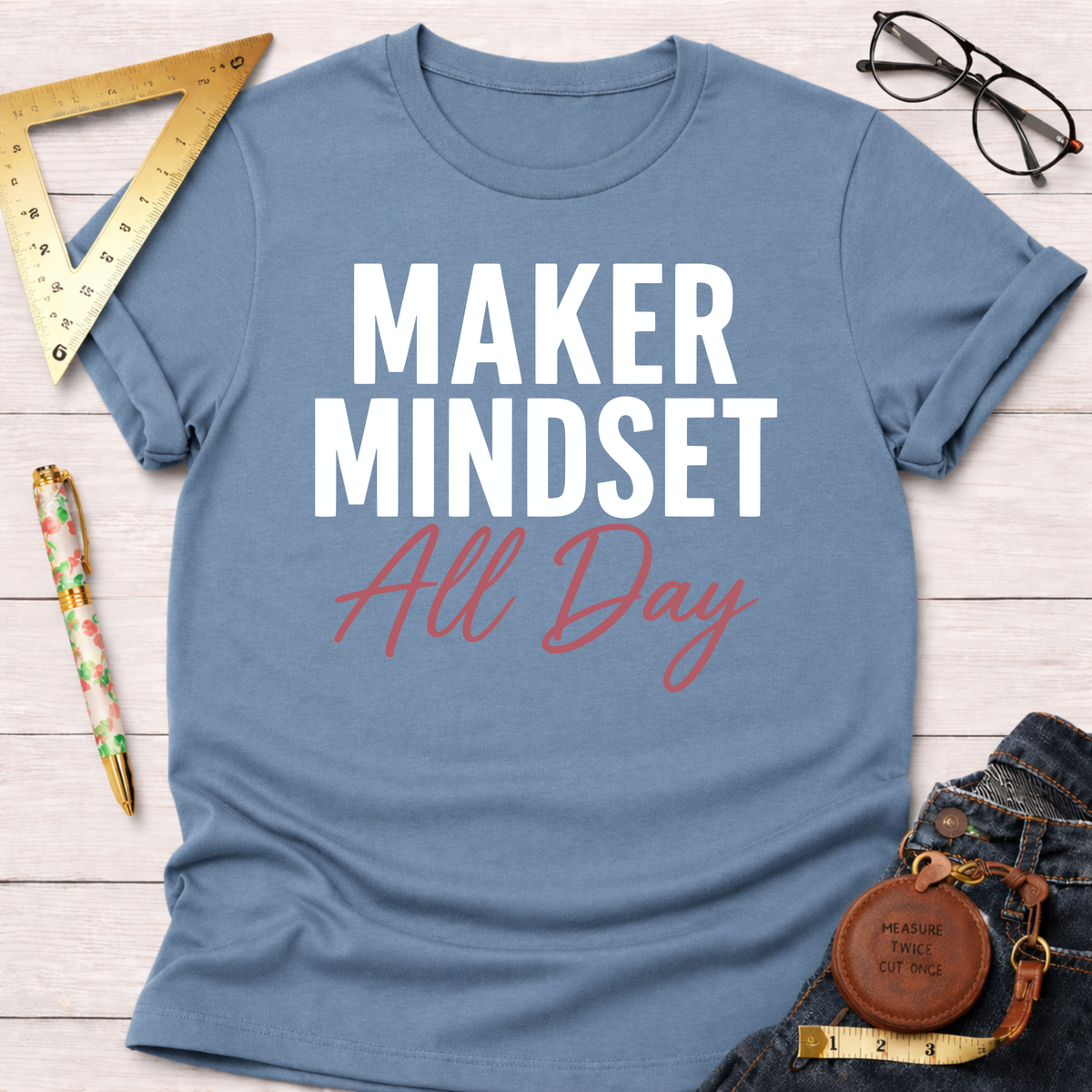 Blue cotton t-shirt with "MAKER MINDSET All Day" graphic, styled with jeans and tools.