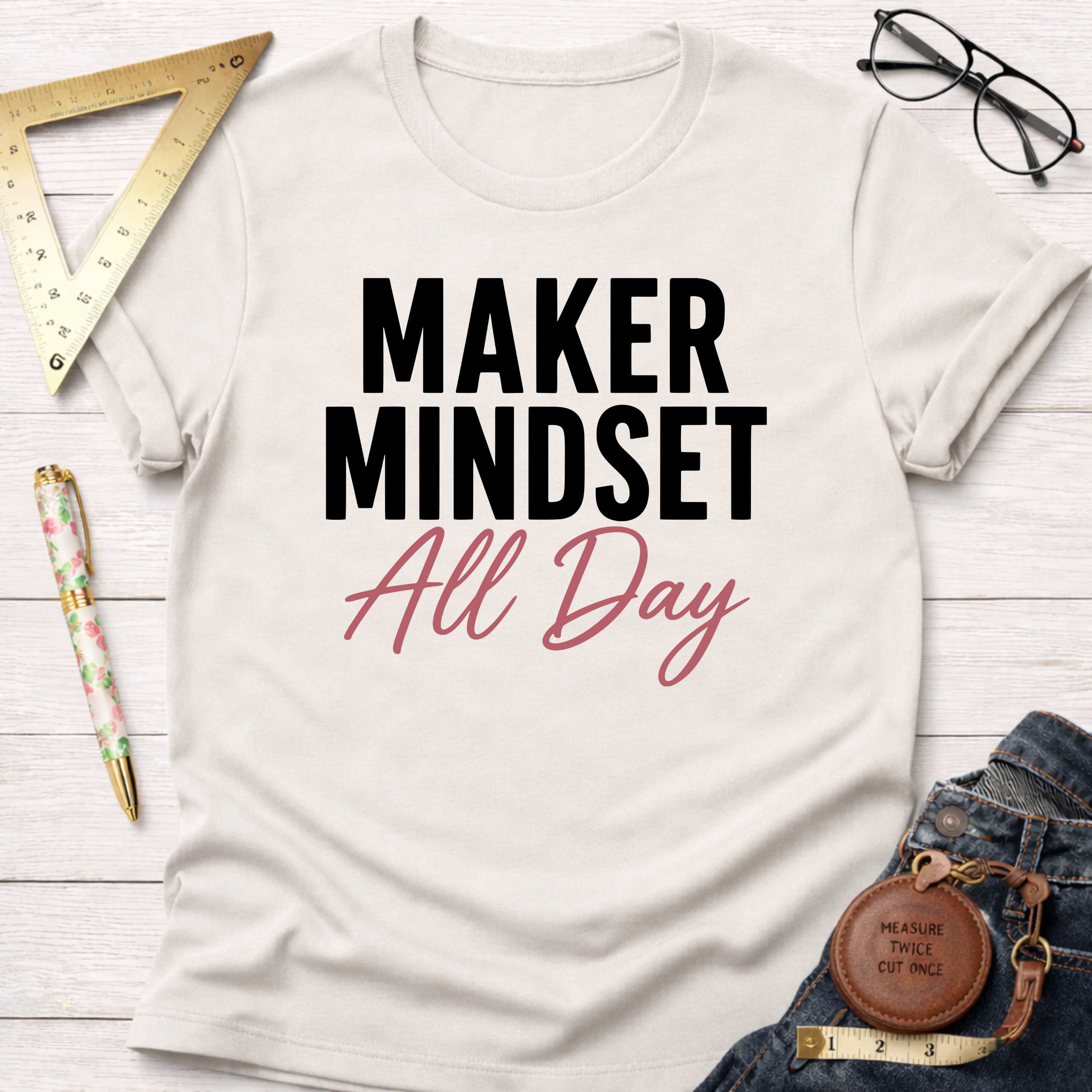 Cream cotton t-shirt with "MAKER MINDSET All Day" graphic, styled with jeans, ruler, pen, and glasses.