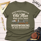 Olive green t-shirt with "Never Underestimate An Old Man Who Still Does Woodworking In His Seventies" text and tools.