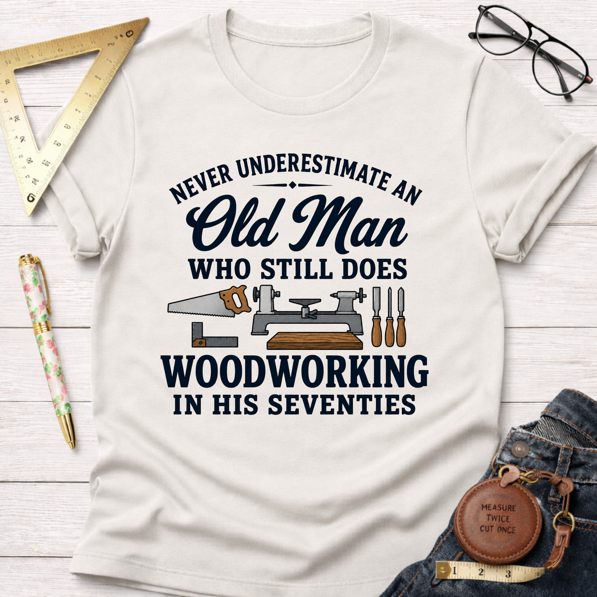 White t-shirt with "Never Underestimate An Old Man Who Still Does Woodworking In His Seventies" text and tools graphic.