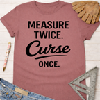 Women's funny woodworking graphic tee shirt for female woodworkers, makers, and DIY builders — Sawdust & Ponytails. Mauve t-shirt with "Measure Twice. Curse Once." in black text.
