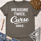 Women's funny woodworking graphic tee shirt for female woodworkers, makers, and DIY builders — Sawdust & Ponytails. Dark gray t-shirt with "MEASURE TWICE. Curse ONCE." in white text.