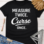 Black cotton Women's funny woodworking graphic tee shirt for female woodworkers, makers, and DIY builders — Sawdust & Ponytails, with "MEASURE TWICE. Curse ONCE." in white text.