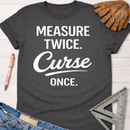 Women's funny woodworking graphic tee shirt for female woodworkers, makers, and DIY builders — Sawdust & Ponytails. Dark gray t-shirt with "MEASURE TWICE. Curse ONCE." in white text.