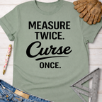 Women's funny woodworking graphic tee shirt for female woodworkers, makers, and DIY builders — Sawdust & Ponytails. Sage green cotton t-shirt with "Measure Twice. Curse Once." in black text.