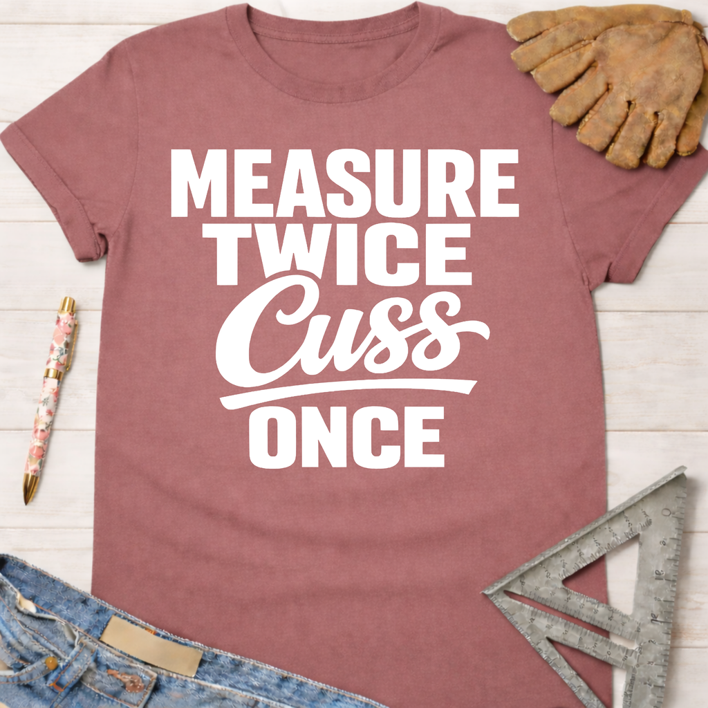 Women's funny woodworking graphic tee shirt for female woodworkers, makers, and DIY builders — Sawdust & Ponytails. Mauve t-shirt with "Measure Twice Cuss Once" in white text.