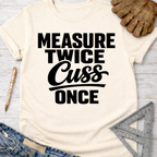 Women's funny woodworking graphic tee shirt for female woodworkers, makers, and DIY builders — Sawdust & Ponytails. Cream t-shirt with "Measure Twice Cuss Once" in black text.