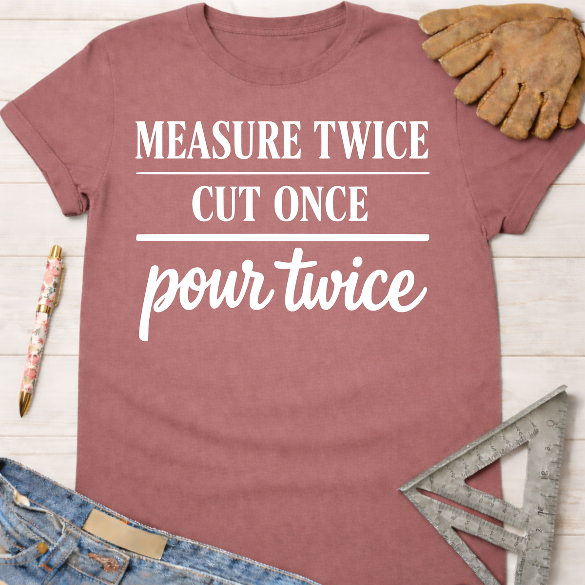 Women's funny woodworking graphic tee shirt for female woodworkers, makers, and DIY builders — Sawdust & Ponytails. Mauve short-sleeve t-shirt with "MEASURE TWICE CUT ONCE pour twice" in white text.
