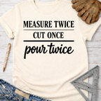 Women's funny woodworking graphic tee shirt for female woodworkers, makers, and DIY builders — Sawdust & Ponytails. Cream t-shirt with "MEASURE TWICE CUT ONCE pour twice" in black text.