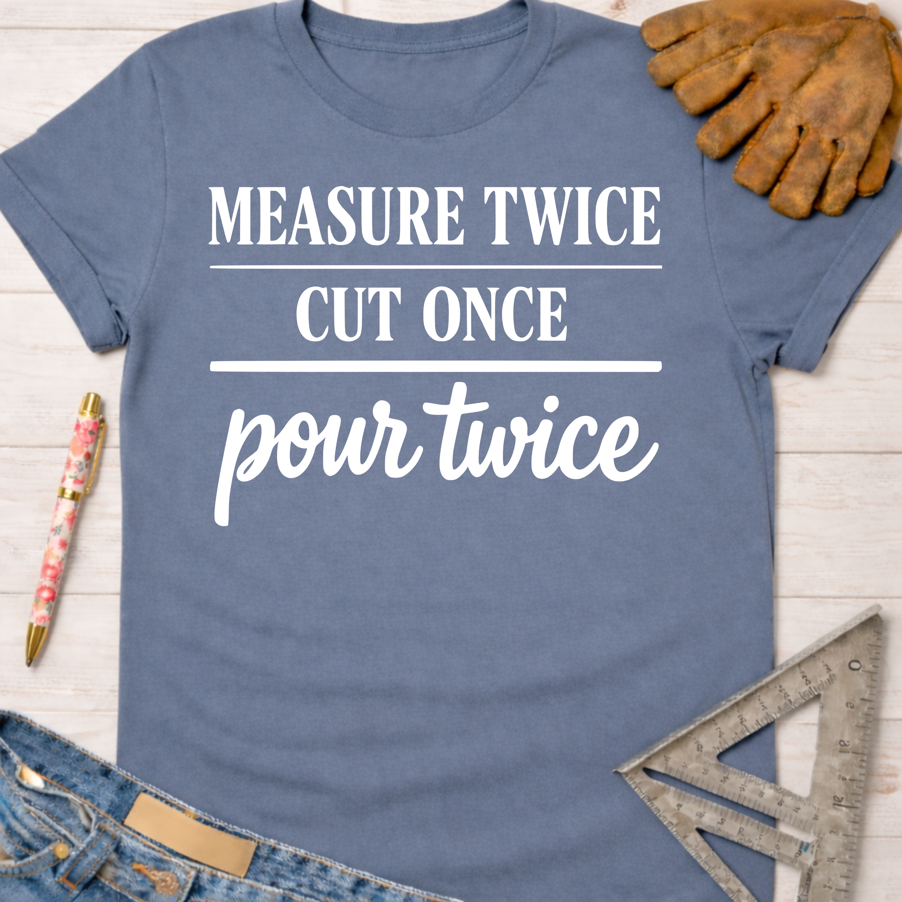 Women's funny woodworking graphic tee shirt for female woodworkers, makers, and DIY builders — Sawdust & Ponytails. Blue cotton tee with "Measure Twice Cut Once Pour Twice" in white text.
