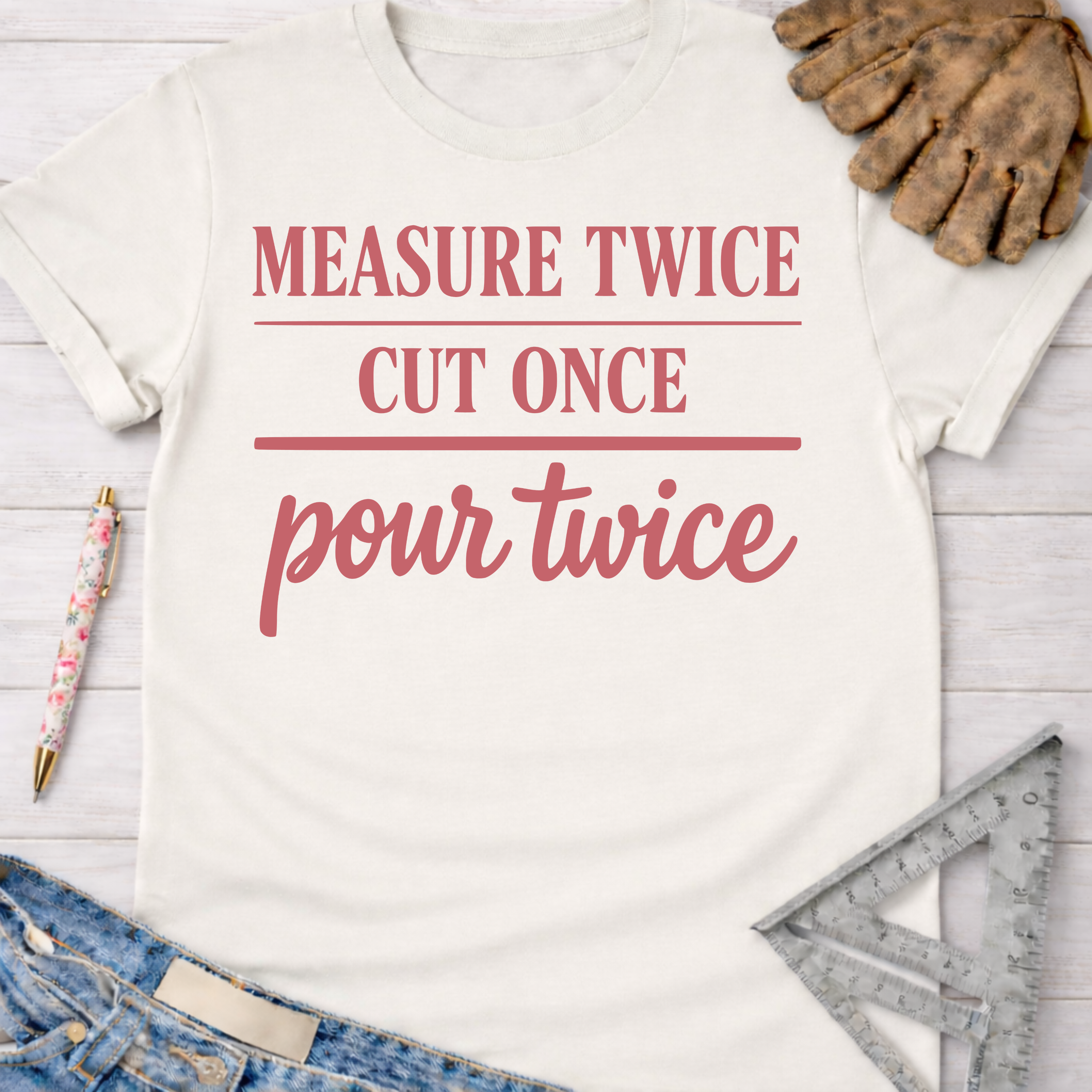 Women's funny woodworking graphic tee shirt for female woodworkers, makers, and DIY builders — Sawdust & Ponytails. White cotton t-shirt with "Measure Twice Cut Once Pour Twice" in pink text.