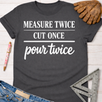 Women's funny woodworking graphic tee shirt for female woodworkers, makers, and DIY builders — Sawdust & Ponytails. Dark gray cotton t-shirt with "MEASURE TWICE CUT ONCE pour twice" in white text.
