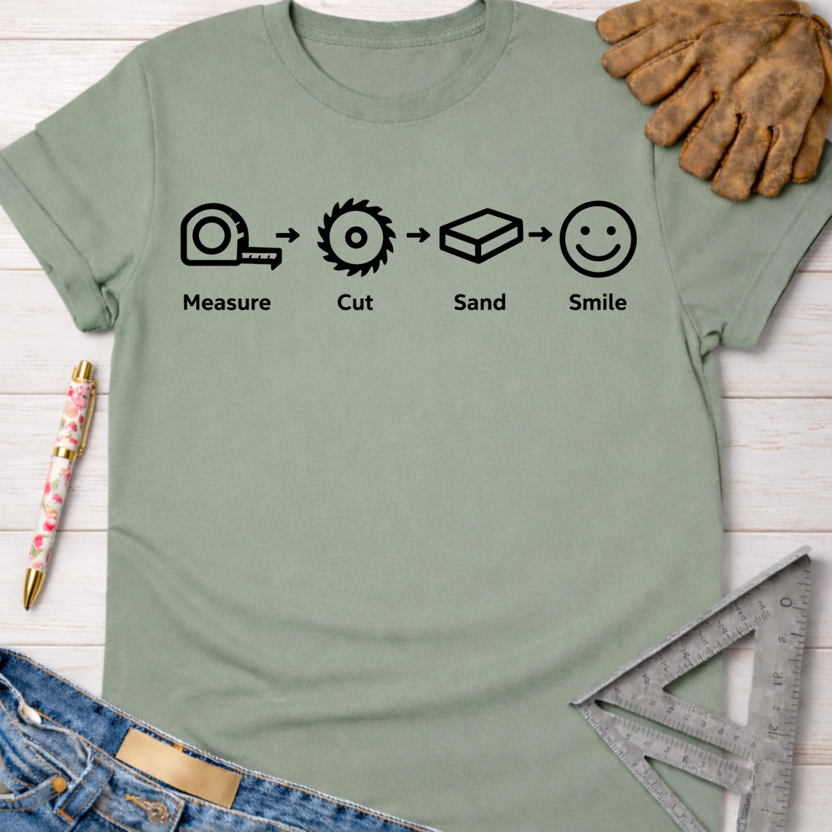 Women's funny woodworking graphic tee shirt for female woodworkers, makers, and DIY builders — Sawdust & Ponytails. Sage green cotton t-shirt with "Measure. Cut. Sand. Smile." graphic.