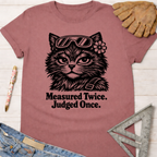 Women's funny woodworking graphic tee shirt for female woodworkers, makers, and DIY builders — Sawdust & Ponytails. Mauve t-shirt with a black graphic of a cat wearing goggles and a flower, text reads "Measured Twice. Judged Once.
