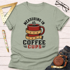 Light green cotton t-shirt with "Measuring In Coffee Cups" graphic featuring a red coffee mug wrapped in a measuring tape.