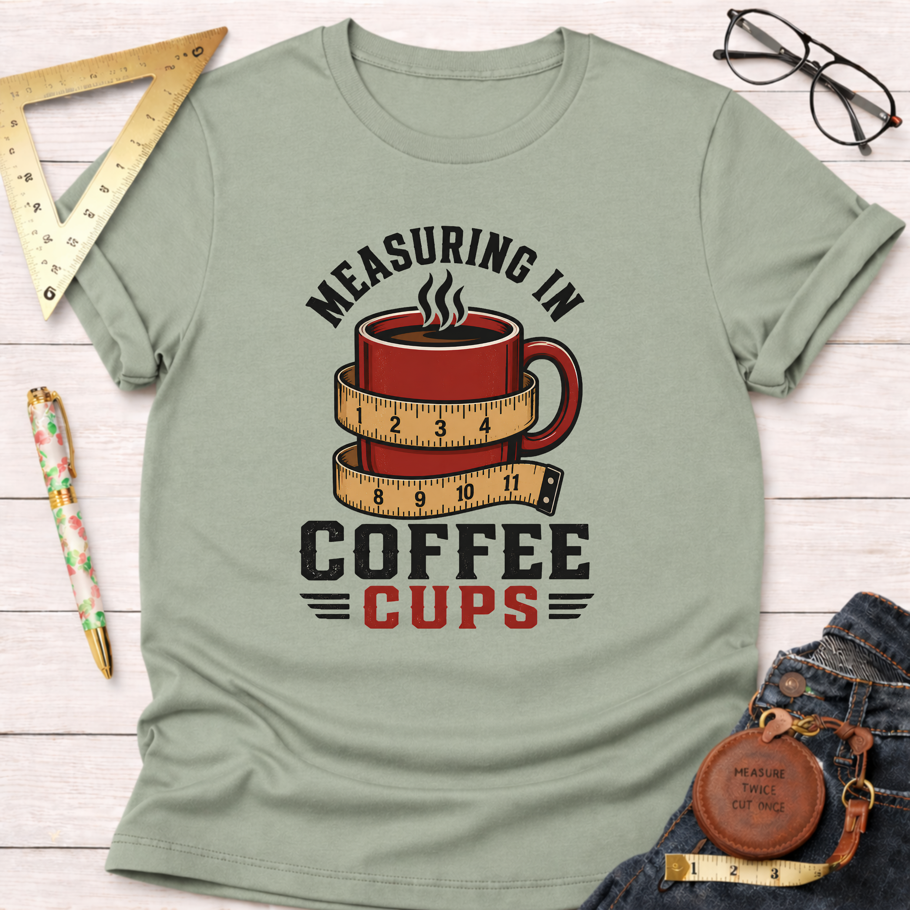 Light green cotton t-shirt with "Measuring In Coffee Cups" graphic featuring a red coffee mug wrapped in a measuring tape.