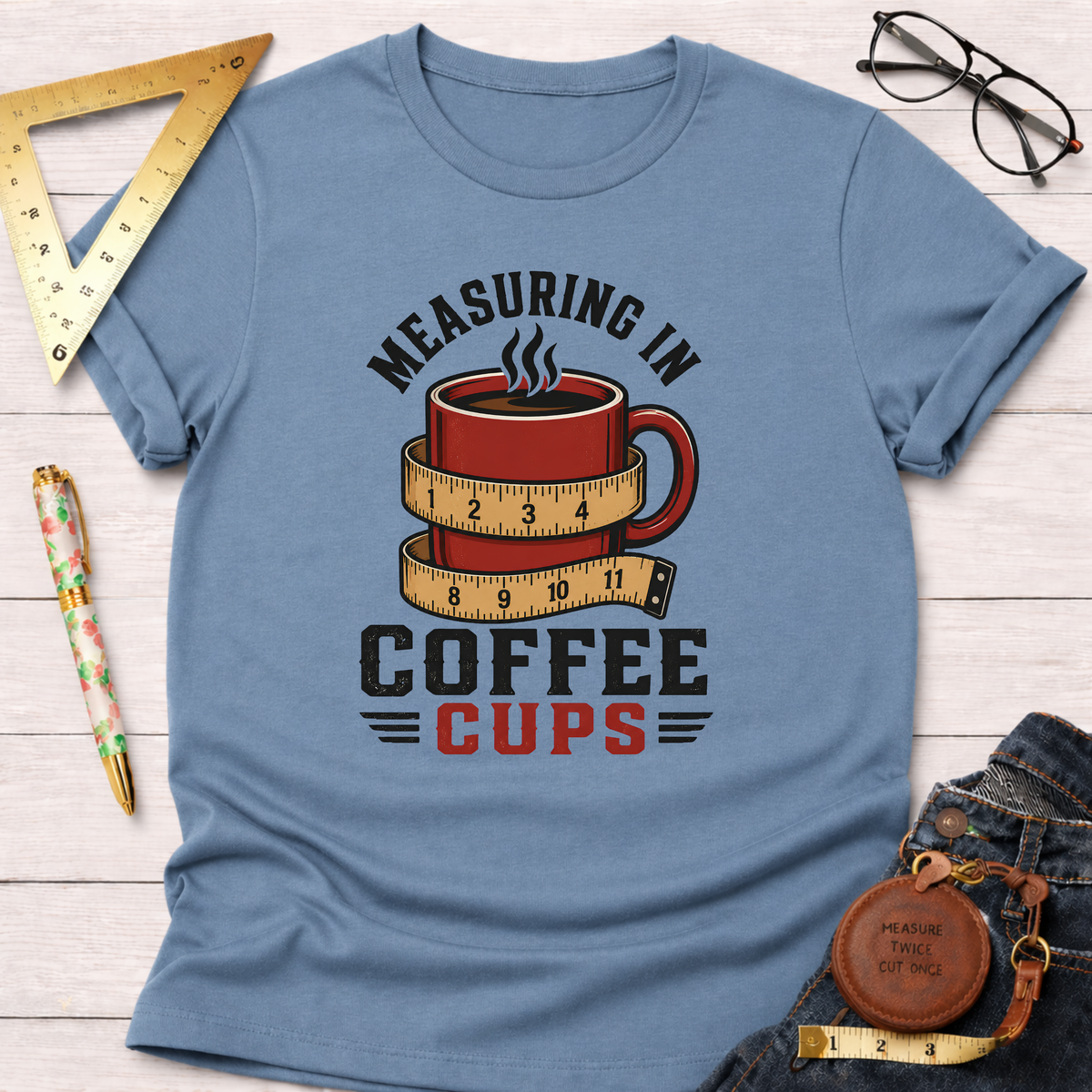 Blue t-shirt with "Measuring In Coffee Cups" text and a red coffee mug wrapped in a measuring tape design.