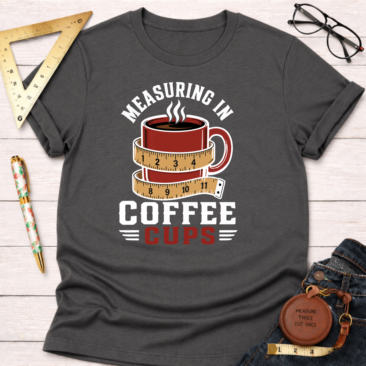 Charcoal gray t-shirt with "Measuring In Coffee Cups" design featuring a red coffee mug wrapped in a measuring tape.