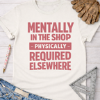 White cotton tee with "Mentally In The Shop Physically Required Elsewhere" in pink text. Women's funny woodworking graphic tee shirt for female woodworkers, makers, and DIY builders — Sawdust & Ponytails.
