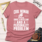Heather dusty rose t-shirt with "Cool Woman Owns A Miter Saw And A Personality Problem" graphic.