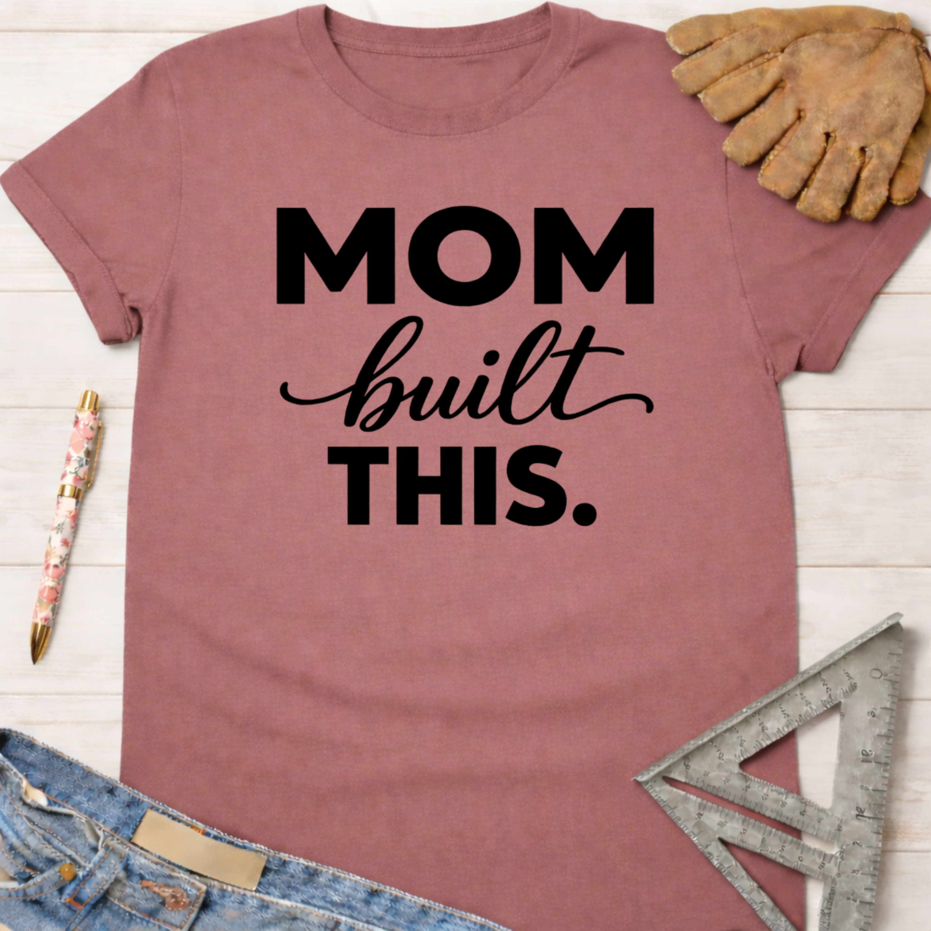 Women's funny woodworking graphic tee shirt for female woodworkers, makers, and DIY builders — Sawdust & Ponytails. Mauve t-shirt with "MOM built THIS." in black text.
