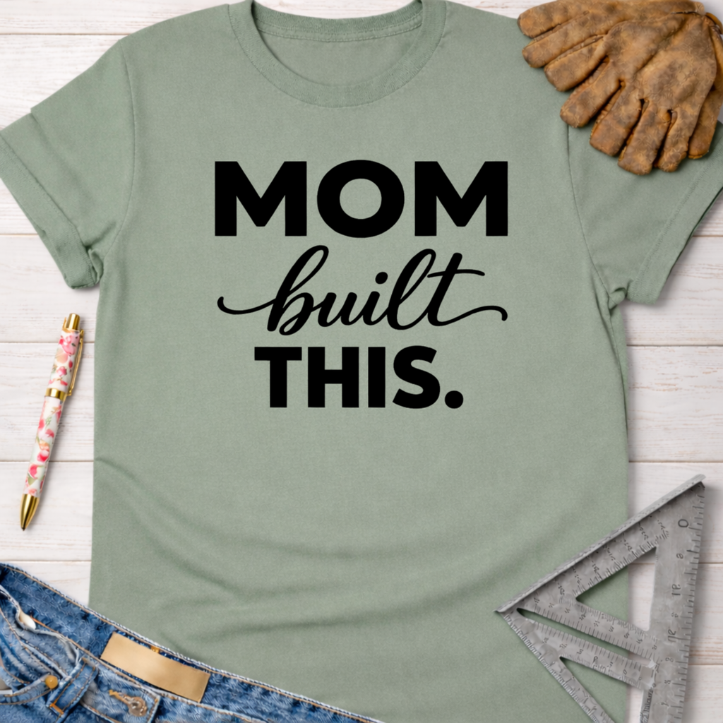 Sage green "Mom built THIS." graphic tee with work gloves, jeans, pen, and ruler. Women's funny woodworking graphic tee shirt for female woodworkers, makers, and DIY builders — Sawdust & Ponytails