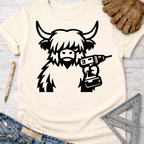 Women's funny woodworking graphic tee shirt for female woodworkers, makers, and DIY builders — Sawdust & Ponytails. Cream t-shirt with a black Highland cow holding a drill.