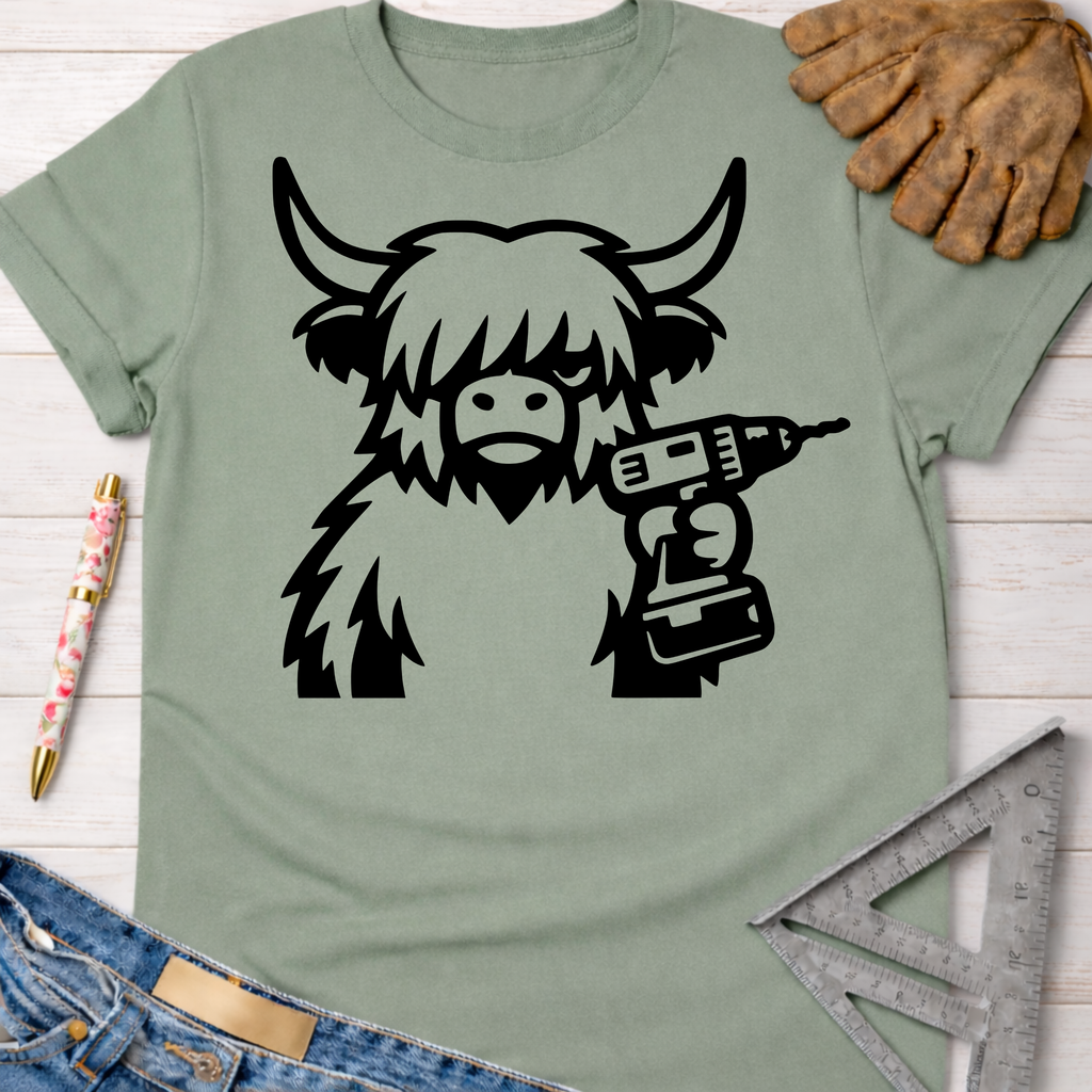 Women's funny woodworking graphic tee shirt for female woodworkers, makers, and DIY builders — Sawdust & Ponytails. Sage green t-shirt with a black graphic of a shaggy Highland cow holding a power drill.