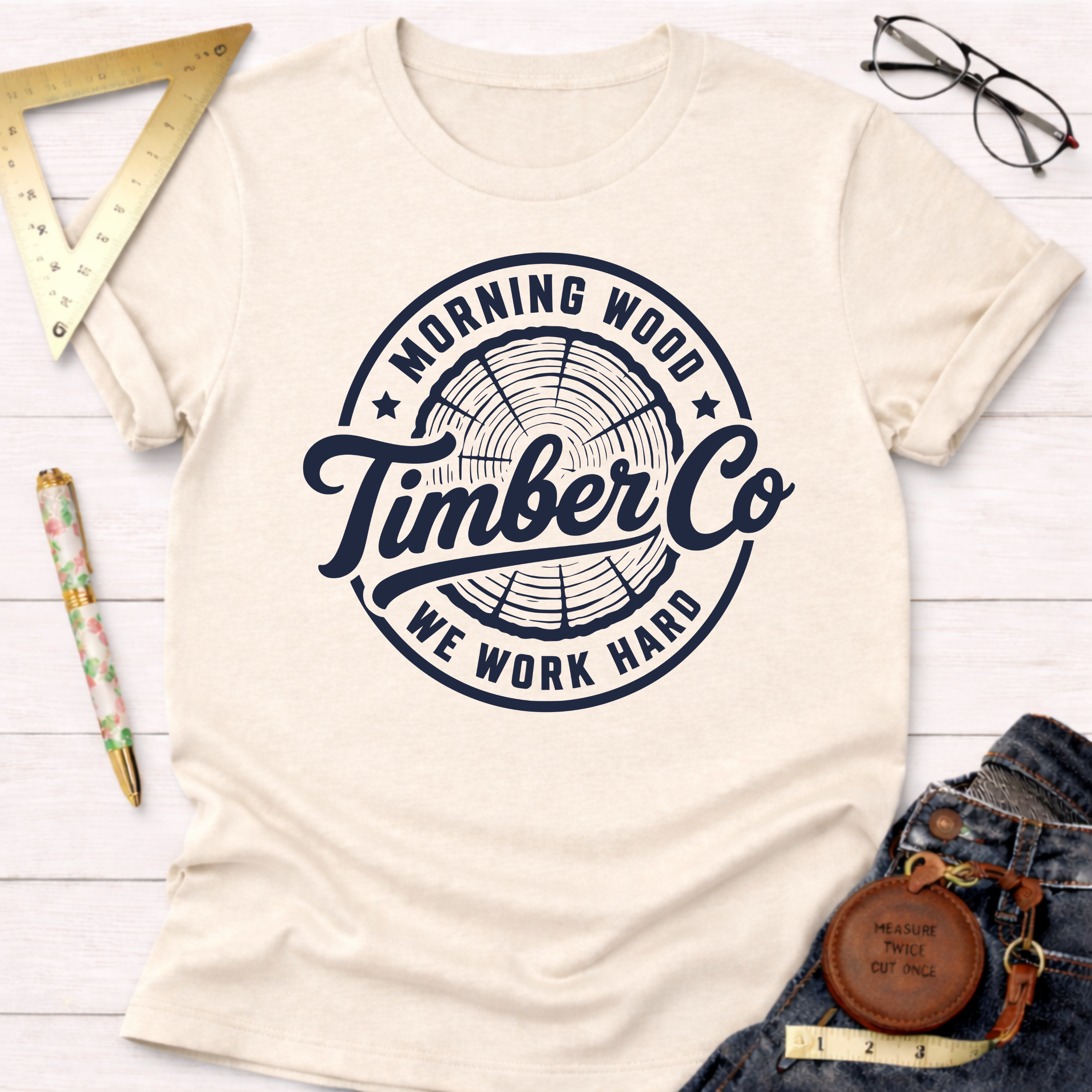 Morning Wood Timber Co. cream t-shirt with a dark blue tree ring logo.