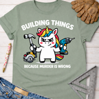 Women's funny woodworking graphic tee shirt for female woodworkers, makers, and DIY builders — Sawdust & Ponytails. Light green cotton t-shirt with a cartoon unicorn holding a hammer and power drill, "BUILDING THINGS BECAUSE MURDER IS WRONG" text.