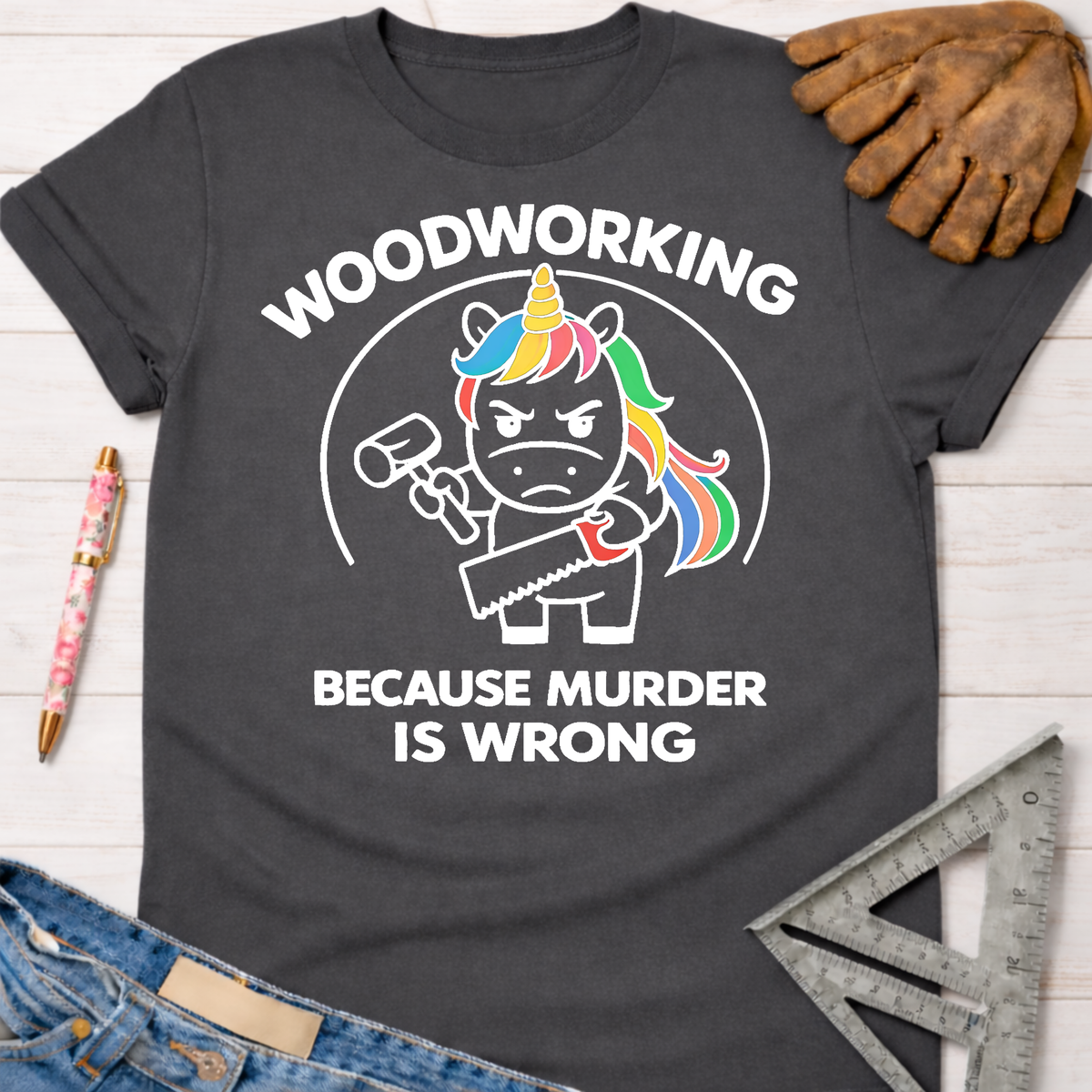 Charcoal gray women's funny woodworking graphic tee with a murderous unicorn holding a hammer and saw. Sawdust & Ponytails.
