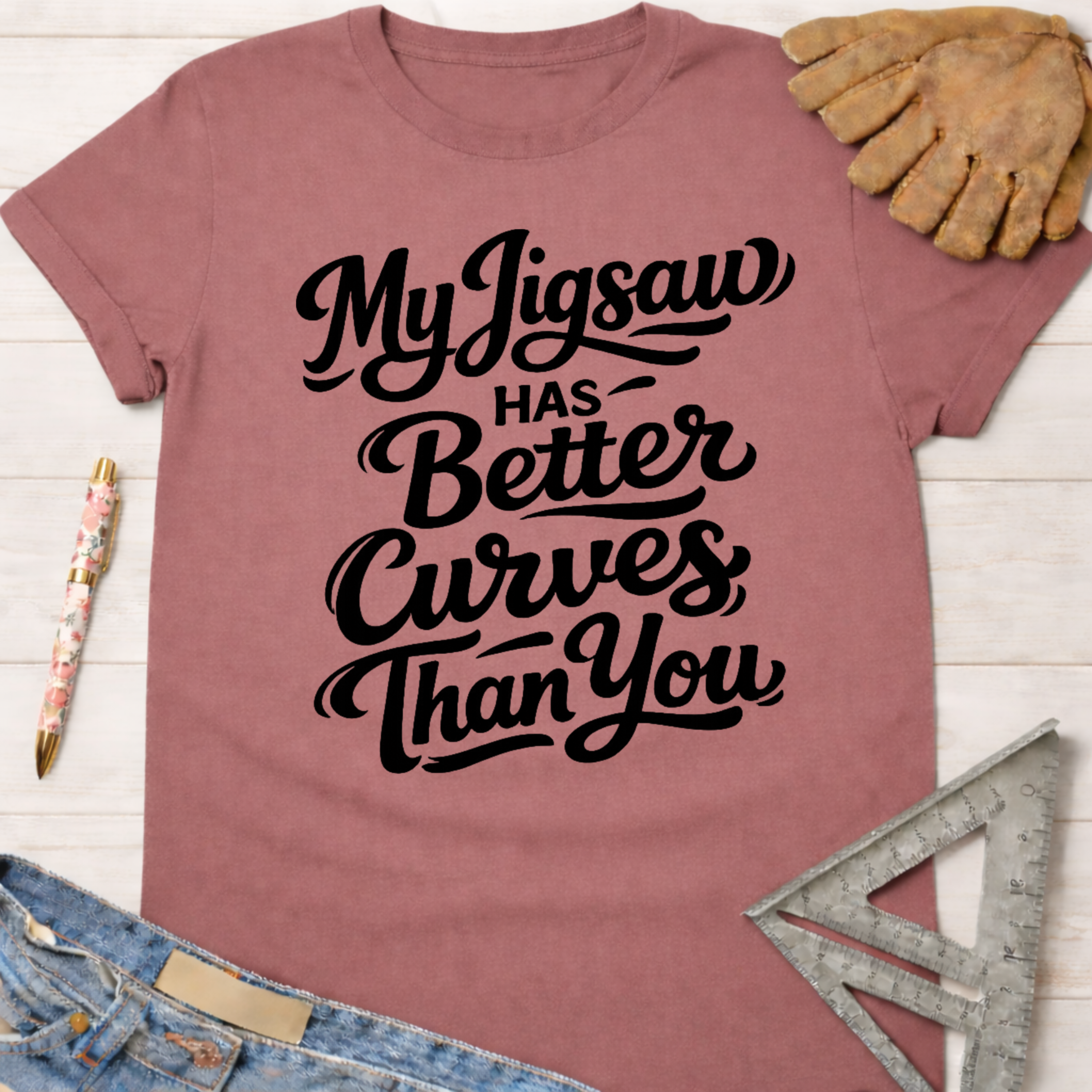 Women's funny woodworking graphic tee shirt for female woodworkers, makers, and DIY builders — Sawdust & Ponytails. Mauve t-shirt with "My Jigsaw Has Better Curves Than You" in black script.
