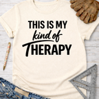 Women's funny woodworking graphic tee shirt for female woodworkers, makers, and DIY builders — Sawdust & Ponytails. Cream short-sleeve t-shirt with "THIS IS MY kind of THERAPY" in black text.