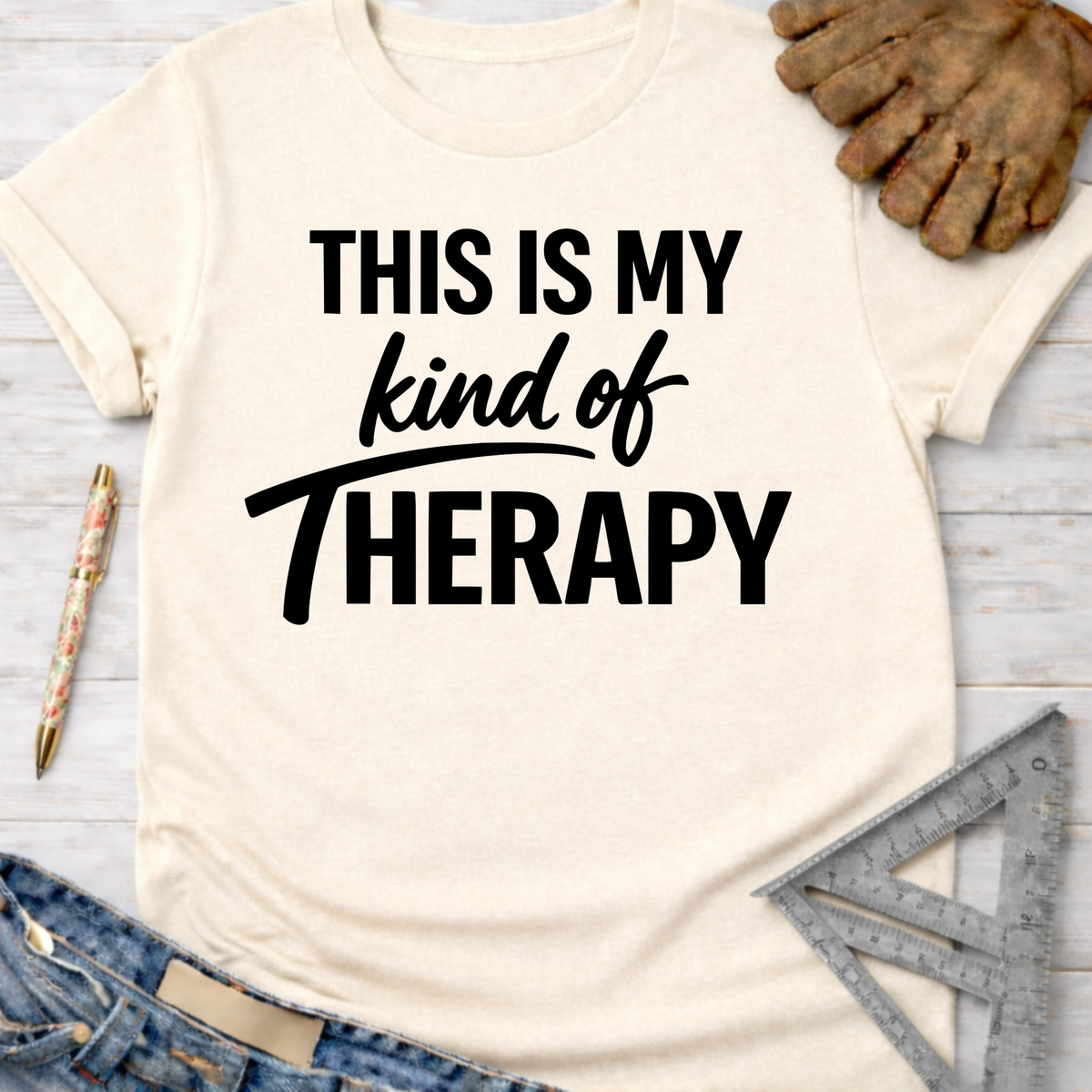 Women's funny woodworking graphic tee shirt for female woodworkers, makers, and DIY builders — Sawdust & Ponytails. Cream short-sleeve t-shirt with "THIS IS MY kind of THERAPY" in black text.