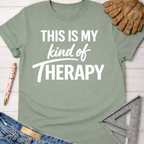 Women's funny woodworking graphic tee shirt for female woodworkers, makers, and DIY builders — Sawdust & Ponytails. Sage green cotton tee with "THIS IS MY kind of THERAPY" in white text.