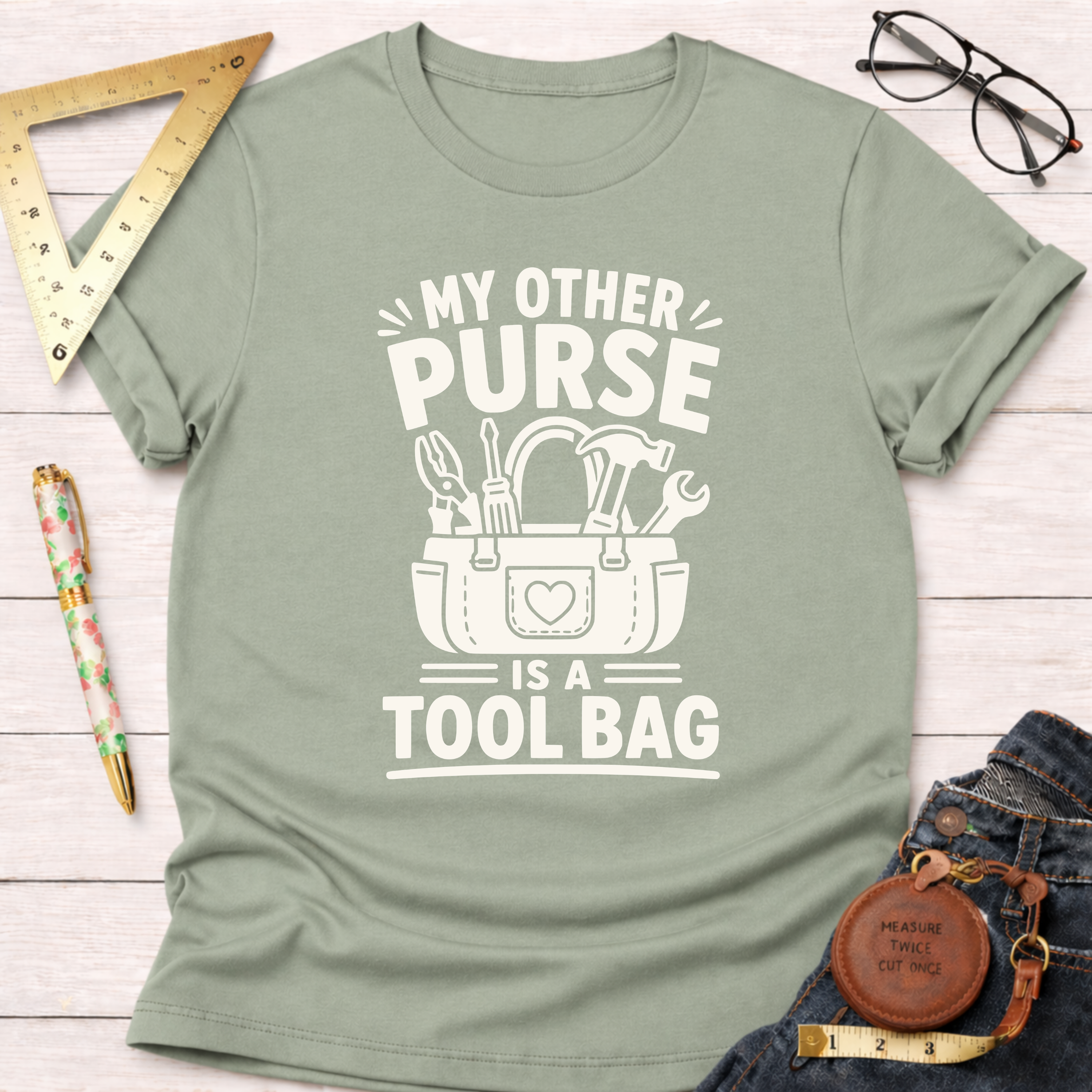 Sage green t-shirt with "My Other Purse Is a Tool Bag" white graphic featuring a tool bag design.