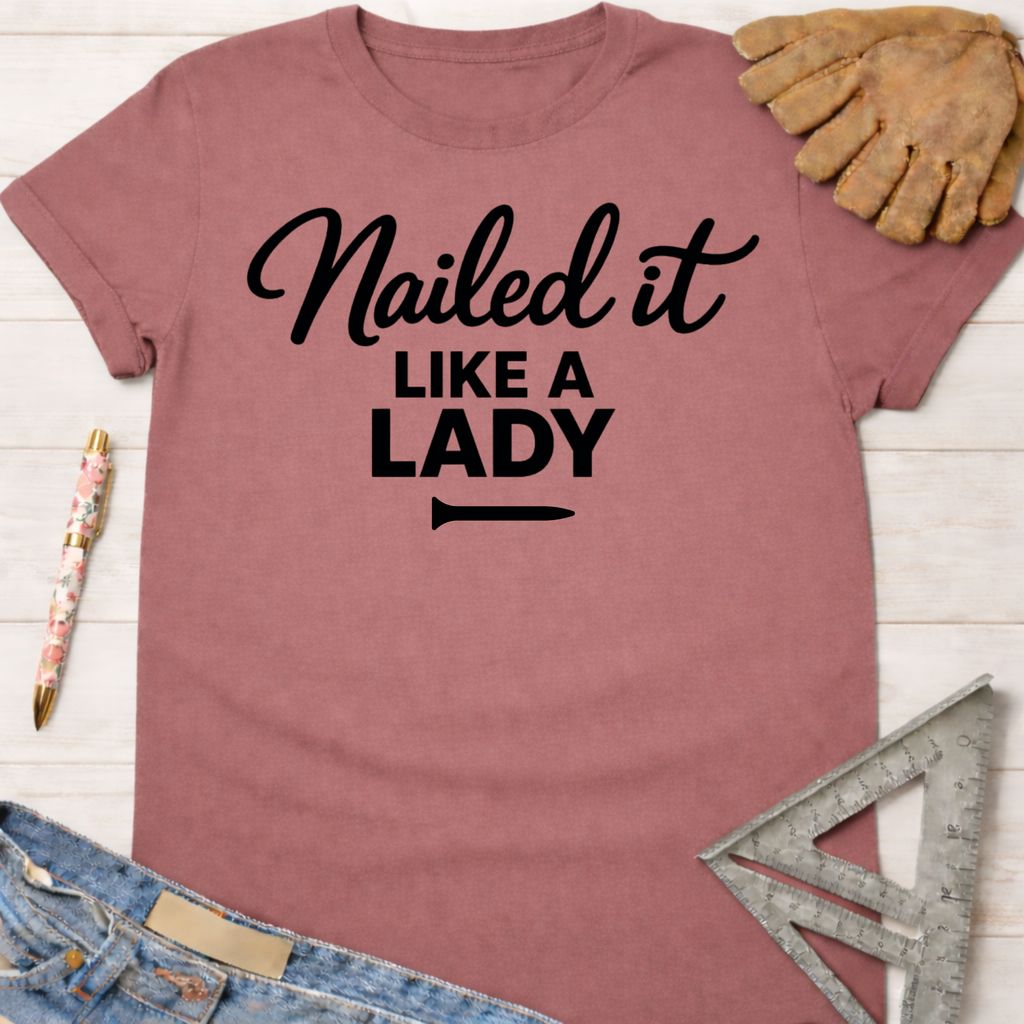 Women's funny woodworking graphic tee shirt for female woodworkers, makers, and DIY builders — Sawdust & Ponytails. Mauve cotton tee with "Nailed it LIKE A LADY" in black script.