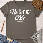 Women's funny woodworking graphic tee shirt for female woodworkers, makers, and DIY builders — Sawdust & Ponytails. Dark gray cotton tee with "Nailed it LIKE A LADY" in white script.