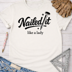 Women's funny woodworking graphic tee shirt for female woodworkers, makers, and DIY builders — Sawdust & Ponytails. White cotton t-shirt with "Nailed It like a lady" in black script, featuring a nail design.