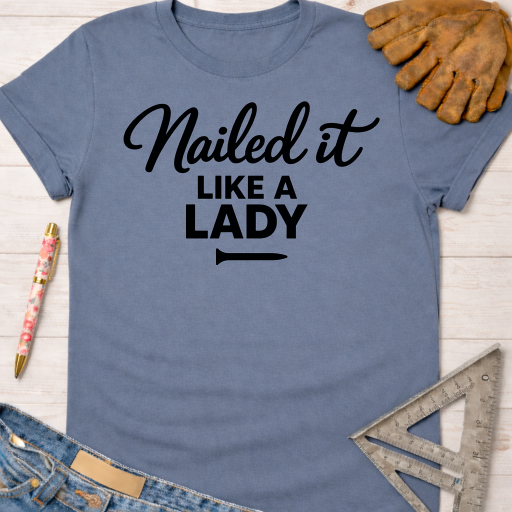 Women's funny woodworking graphic tee shirt for female woodworkers, makers, and DIY builders — Sawdust & Ponytails. Blue cotton tee with "Nailed it LIKE A LADY" in black script.
