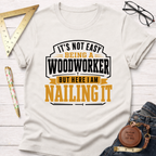 White cotton "Nailing It" t-shirt with black and gold text for woodworkers, surrounded by tools.