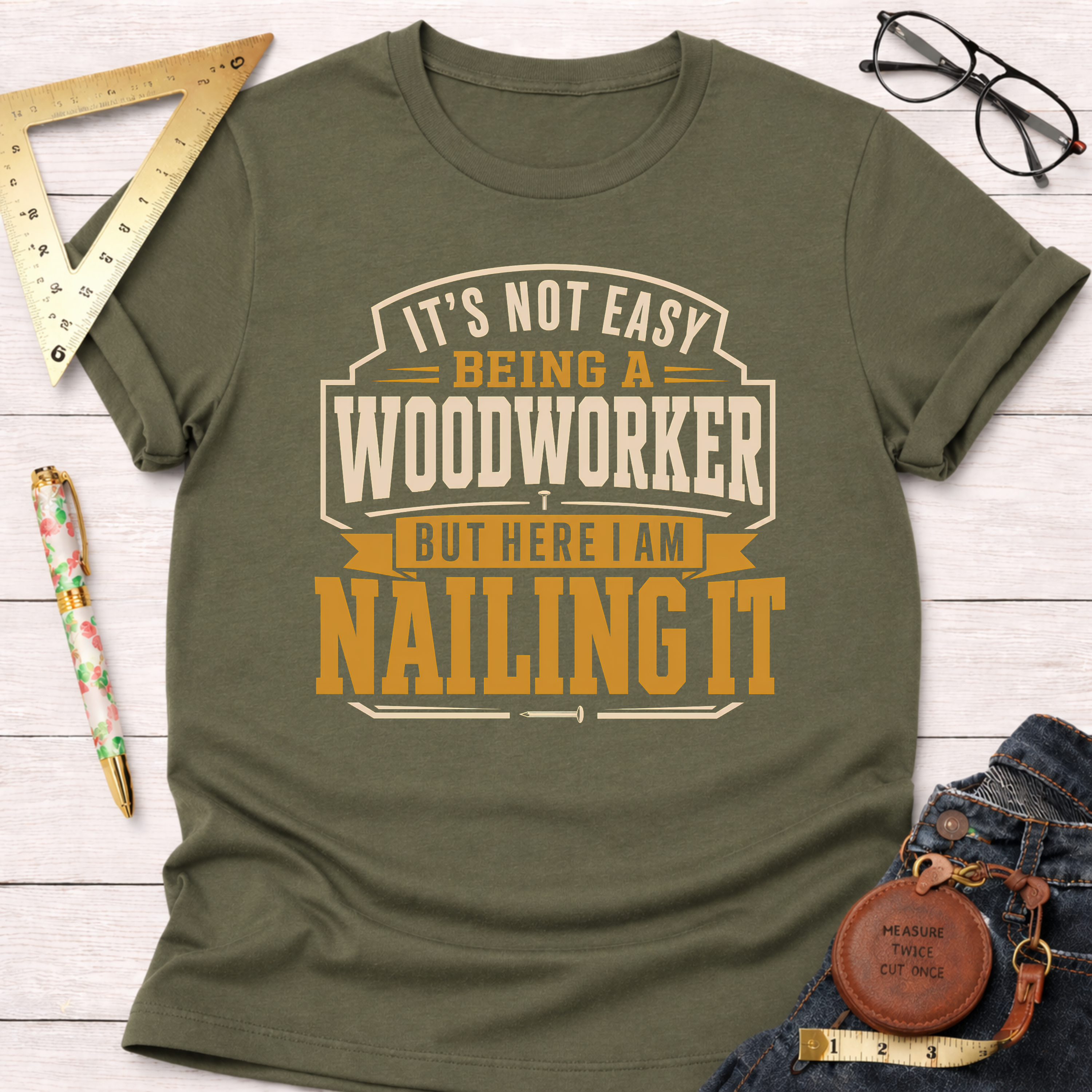Olive green "Nailing It" t-shirt for woodworkers, featuring a bold graphic design in cream and orange.