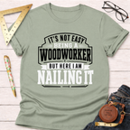 Sage green cotton t-shirt with "Nailing It" woodworking graphic in black and white text.