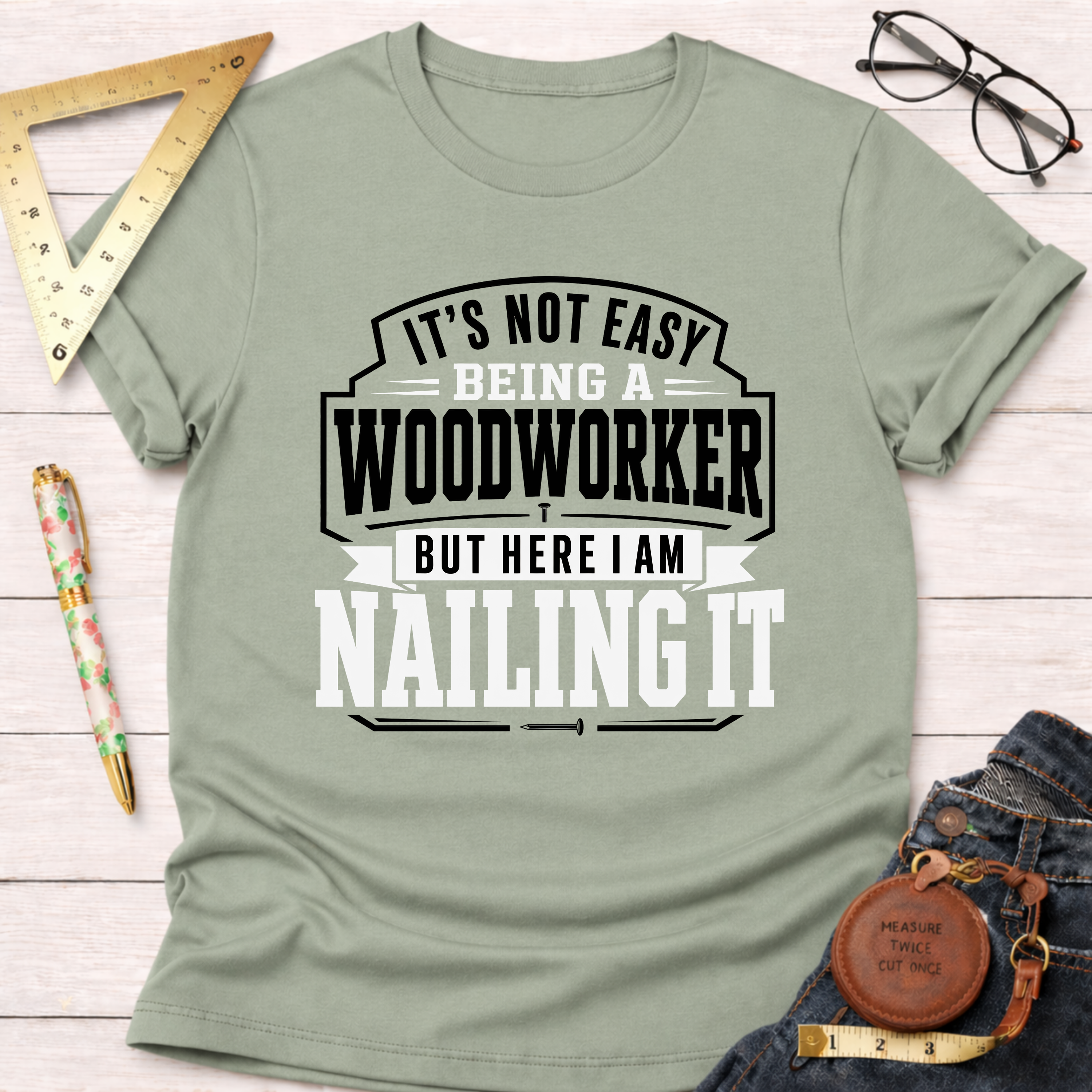Sage green cotton t-shirt with "Nailing It" woodworking graphic in black and white text.