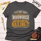 Dark gray cotton t-shirt with "It's Not Easy Being A Woodworker But Here I Am Nailing It" design.