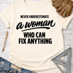 Women's funny woodworking graphic tee shirt for female woodworkers, makers, and DIY builders — Sawdust & Ponytails. Cream t-shirt with "Never Underestimate A Woman Who Can Fix Anything" in black text.